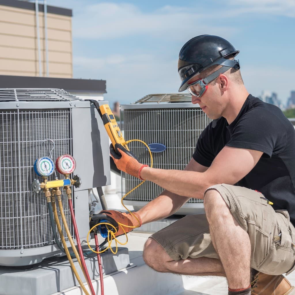 HVAC technician servicing a commercial rooftop unit with diagnostic tools