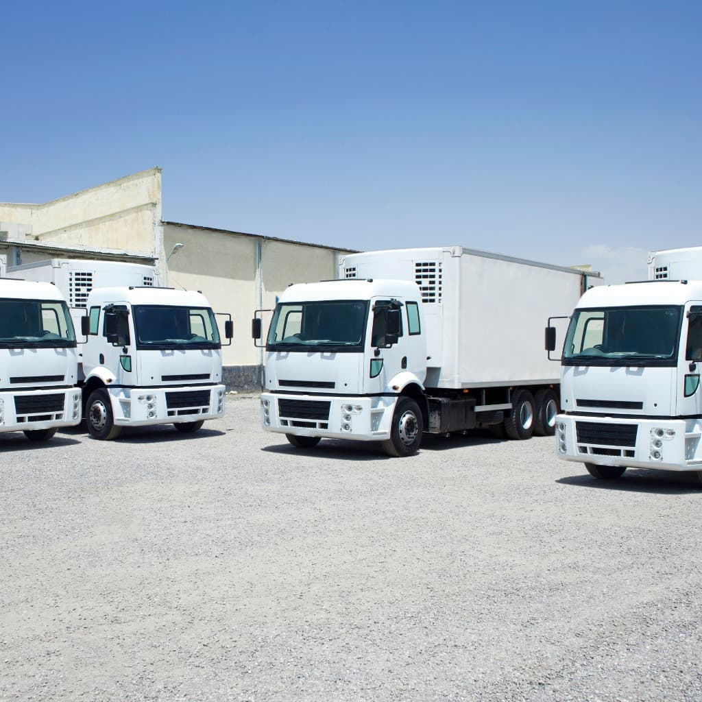 Fleet of white delivery trucks parked at a franchise distribution depot