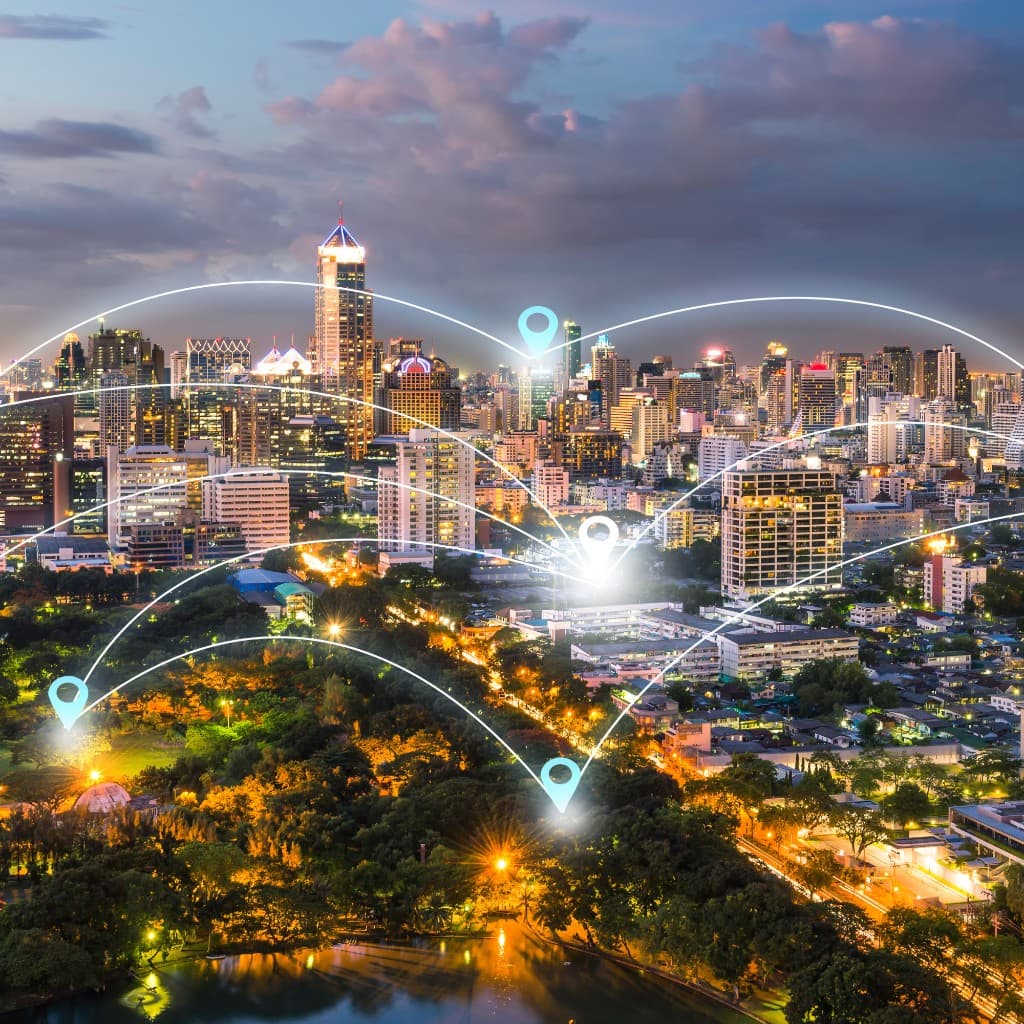 City skyline at dusk with connected location pins across multiple sites