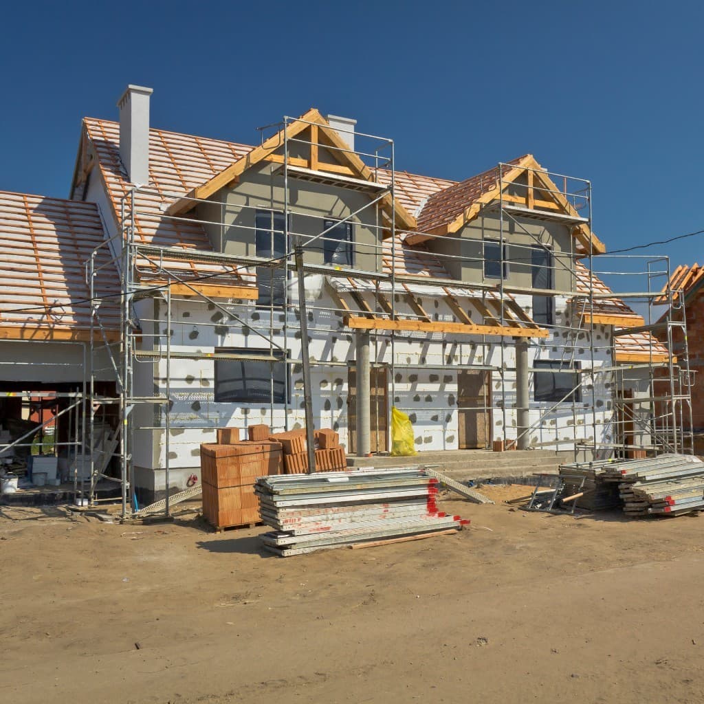 Two-story residential home under construction with scaffolding and building materials