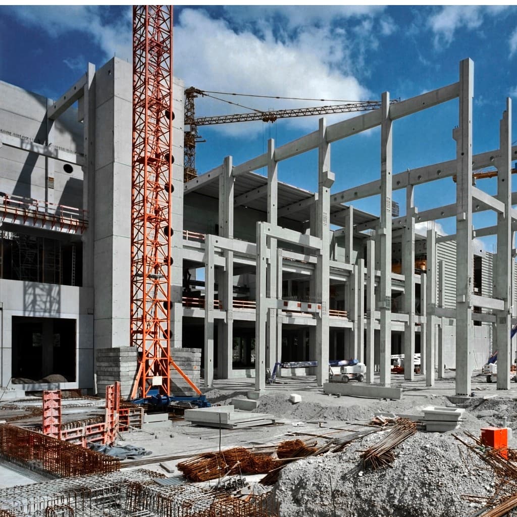 Large commercial construction site with concrete structure and tower crane under a clear sky